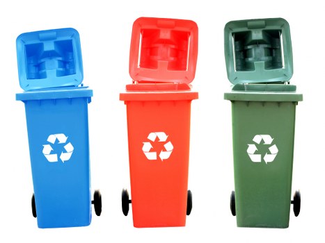 The image displays three distinct wheelie bins arranged side by side on a plain white background. The left bin is blue with a partially open lid, revealing a textured, ribbed interior. The middle bin is red with its lid also slightly open, showing a similar ribbed interior surface. The right bin is green with a lid fully open, exposing a textured, ribbed inside resembling typical waste collection containers. All three bins are made of sturdy plastic with smooth, matte finishes, and each features a prominent white recycling symbol printed on the front. The red, blue, and green bins are equipped with black wheels at the base for mobility, and the background is neutral, emphasizing the vibrant colours of the bins. Such waste containers are commonly used for segregated rubbish collection, supporting environmentally conscious waste management practices often implemented by waste disposal services like Commercial Waste Woking, especially in the Woking postcode area. The lighting evenly illuminates the bins, clearly showcasing their textures and colour tones, and the overall arrangement suggests an organized waste sorting setup.